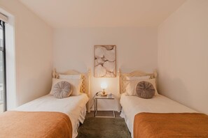Une chambre avec deux lits, une table de chevet avec une lampe et une œuvre d’art accrochée au mur.