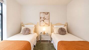 A hotel room with two beds, a nightstand with a lamp, and a wall-mounted artwork.
