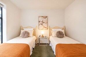 A hotel room with two beds, a nightstand with a lamp, and a wall-mounted artwork. - CBD 2BR Retreat | Private Garden + BBQ (Christchurch)