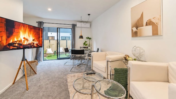 Un salon moderne avec une cheminée, un canapé, une table basse et un coin repas avec des chaises.