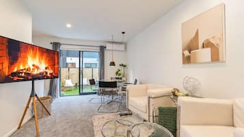 A modern living room with a fireplace, a sofa, a coffee table, and a dining area with chairs.