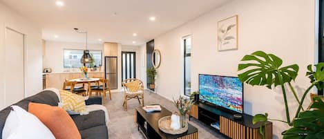Un salon moderne comprenant un canapé, une table basse, un téléviseur et un coin repas.