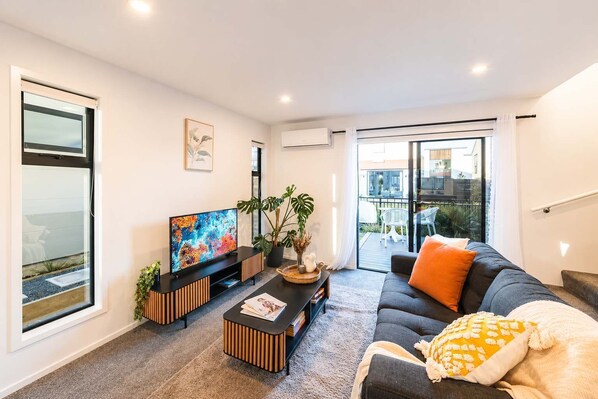 Una sala de estar moderna con un televisor de pantalla plana, un sofá, una mesa de centro y una planta en maceta.