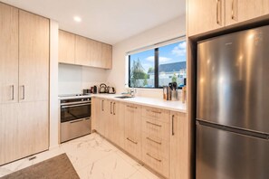 Una cocina moderna con armarios de madera clara, electrodomésticos de acero inoxidable y un ventanal con vistas al exterior.