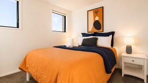 Um quarto com uma cama, uma mesa de cabeceira, uma luminária e um quadro na parede.
