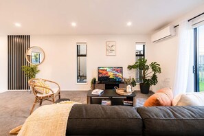 A modern living room with a sofa, a television, and a dining table.