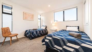 A hotel room with two beds, a chair, a nightstand, and a window.