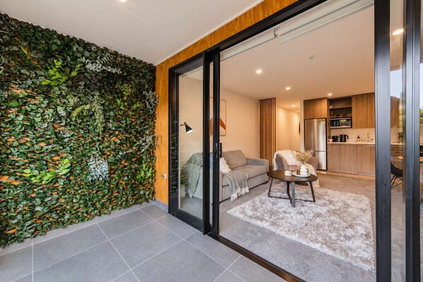 A modern interior with a living area, a kitchen, and a glass door leading to a balcony.
