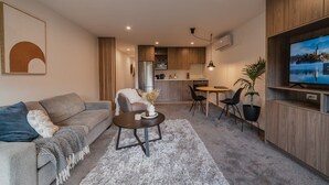 Een moderne woonkamer met een bank, salontafel en een aan de muur bevestigde televisie.
