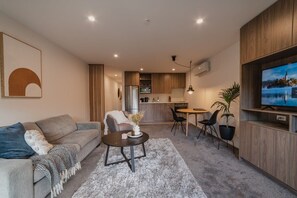 A modern living room with a sofa, coffee table, and a TV on a wooden wall.