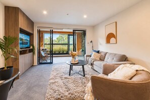 A modern living room with a sofa, a coffee table, and a TV on a wooden cabinet.