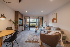 A modern living room with a sofa, coffee table, and dining area.