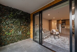 A modern living room with a glass door leading to a kitchen.