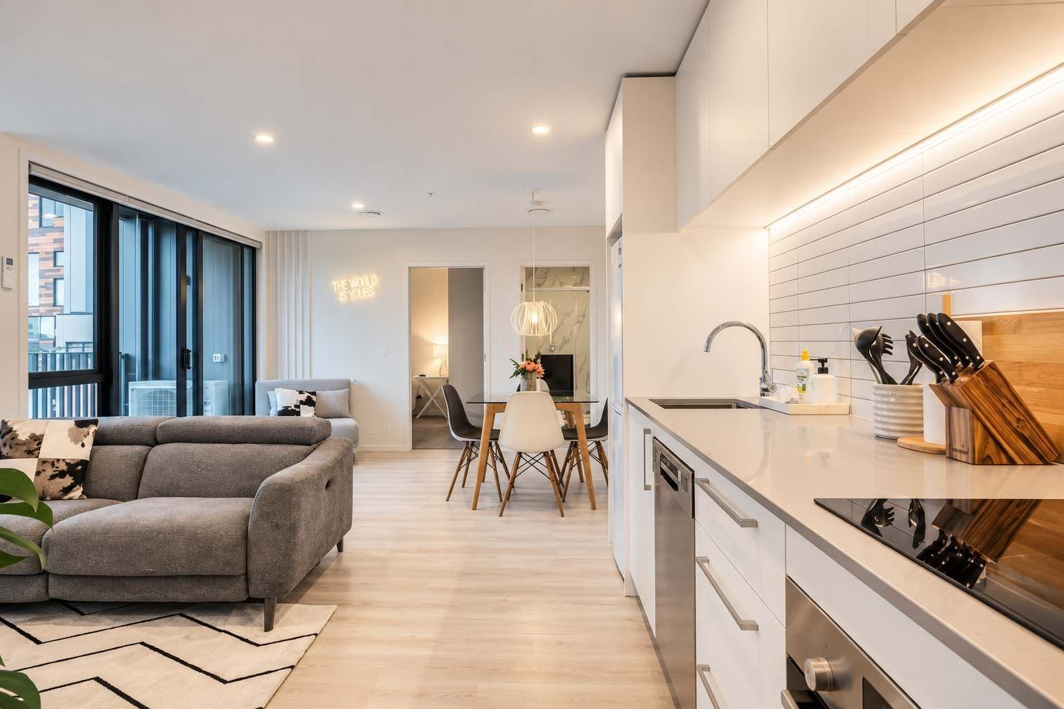 A modern apartment with a living room, dining area, and kitchen.
