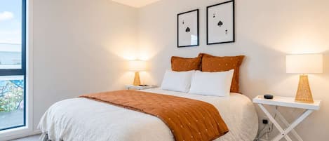 Una camera da letto con un letto, due comodini, una finestra e due carte da gioco incorniciate appese al muro.