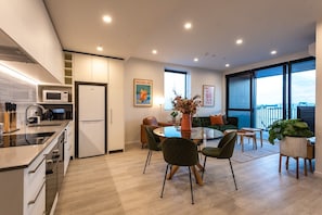 Een moderne keuken met een magnetron, koelkast en een eethoek met een ronde tafel en stoelen.
