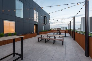 Un patio al aire libre con bancos modernos y luces colgantes.