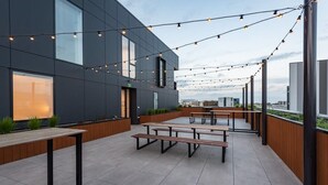 Ein Außenbereich mit einer Terrasse, modernen Bänken und Lichterketten.