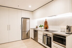Eine moderne Küche mit einem Edelstahl-Kühlschrank, einem Einbauofen und einer Mikrowelle.