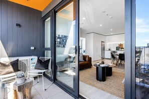 A modern living space with a glass door leading to a kitchen and dining area.