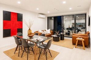 Ein modernes Wohnzimmer mit einem Glastisch, Ledersofas und einem großen abstrakten Gemälde.