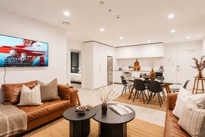 Ein modernes Wohnzimmer mit einer Ledersofa, einem Couchtisch und einem an der Wand befestigten Fernseher.