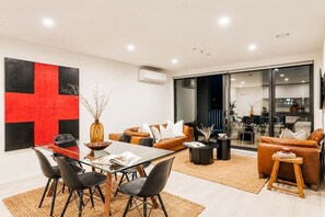 Ein stilvolles Wohnzimmer mit einem Glastisch, Ledersofas und einem großen abstrakten Gemälde.