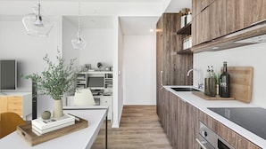 A modern kitchen with wooden cabinets, a central island, and a built-in oven. - The Mason (Toronto)