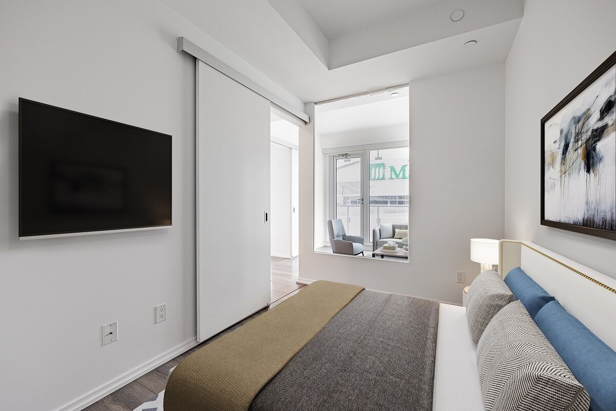 Une chambre d’hôtel moderne avec un lit, une télévision, une grande fenêtre et un tableau.
