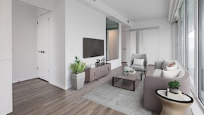 A modern living room with a flat-screen TV, grey sofa, and a coffee table. - The Mason (Toronto)