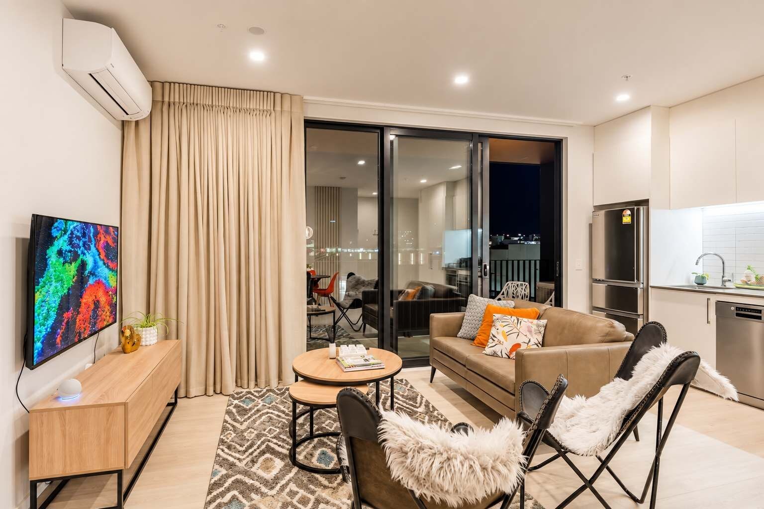 A modern living room with a sofa, chairs, a coffee table, and a flat-screen TV.