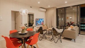 Uma sala moderna com área de jantar, sofá e televisão.