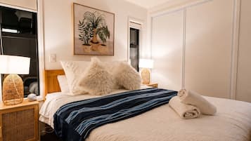 A hotel room with a bed, two bedside lamps, a painting, and a wardrobe.