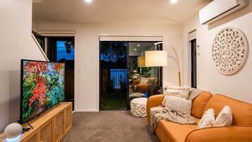 A modern living room with a television, sofa, and decorative wall piece.