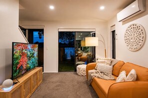 Una sala moderna con televisor, sofá y un elemento decorativo en la pared.