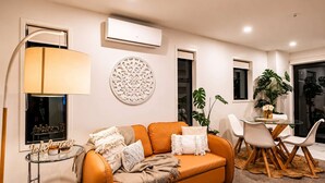 Un salon moderne comprenant un canapé, une table basse en verre, une lampe et un coin repas avec des chaises et une table.