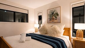 Une chambre d’hôtel avec un lit, une lampe de chevet, une fenêtre et une œuvre d’art accrochée au mur.