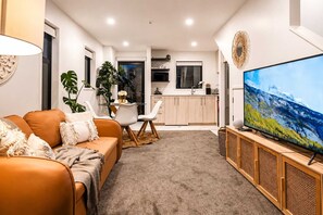 Una sala de estar moderna con un sofá, una mesa de centro y un televisor de pantalla plana sobre un mueble de madera.