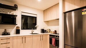 Une cuisine moderne avec des meubles en bois, un réfrigérateur en acier inoxydable, une fenêtre et un évier.