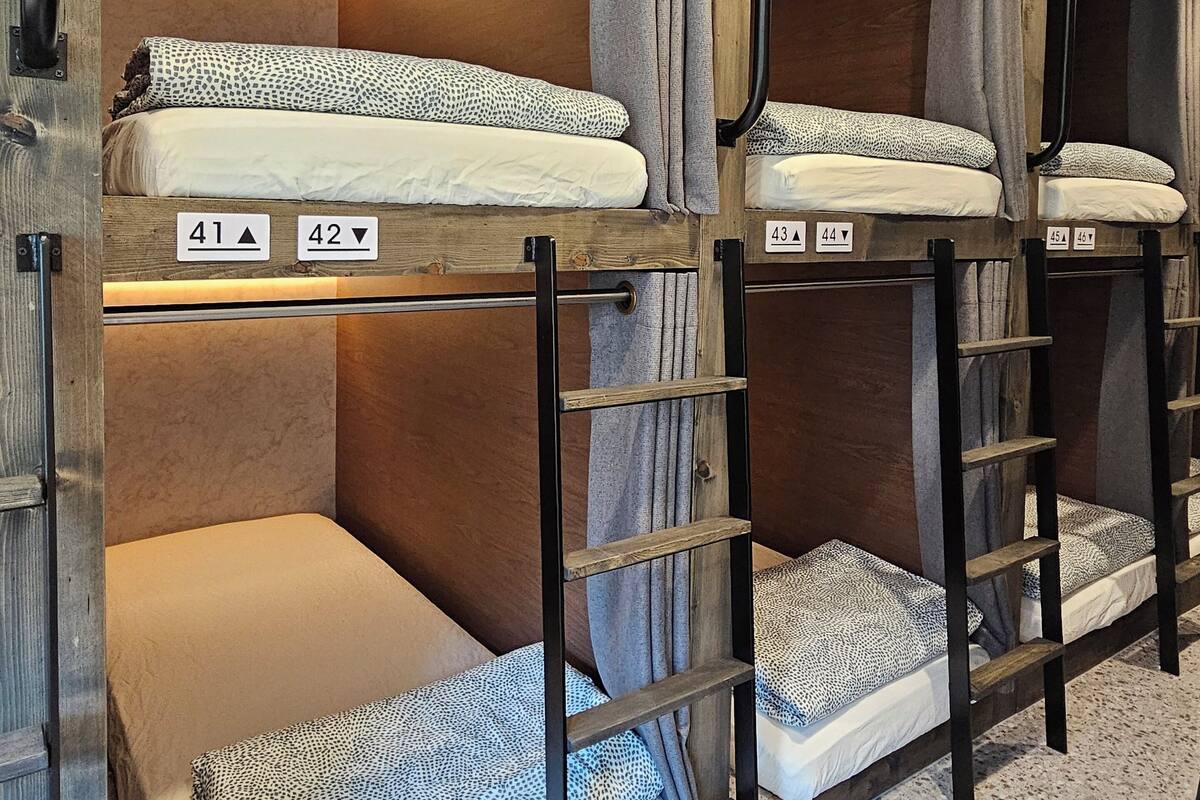 Bunk beds with numbers indicating room assignments, wooden frames, and curtains.