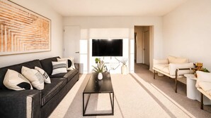 A modern living room with a dark sofa, a coffee table, and a TV.