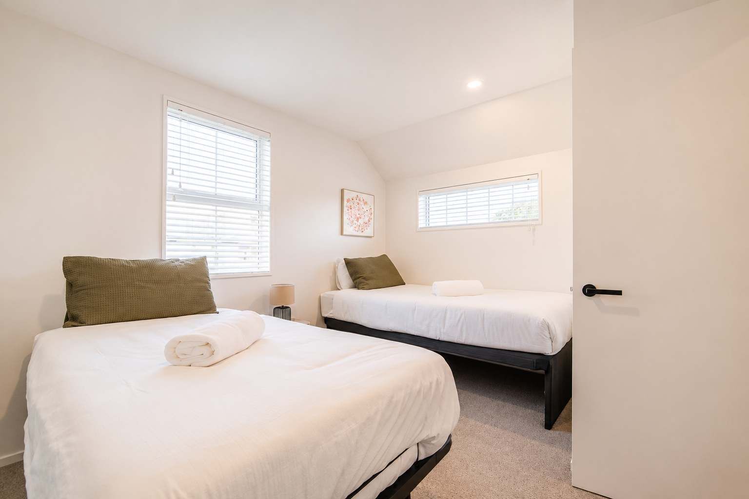 Un dormitorio con dos camas, una puerta y ventanas.