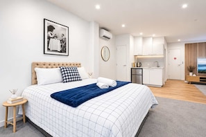 Une chambre d’hôtel moderne dotée d’un grand lit, d’une kitchenette et d’un téléviseur.