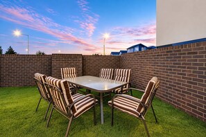 An outdoor patio with a brick wall, a round table, and striped chairs.