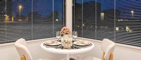 A dining area with a round table, two chairs, and a vase with flowers.