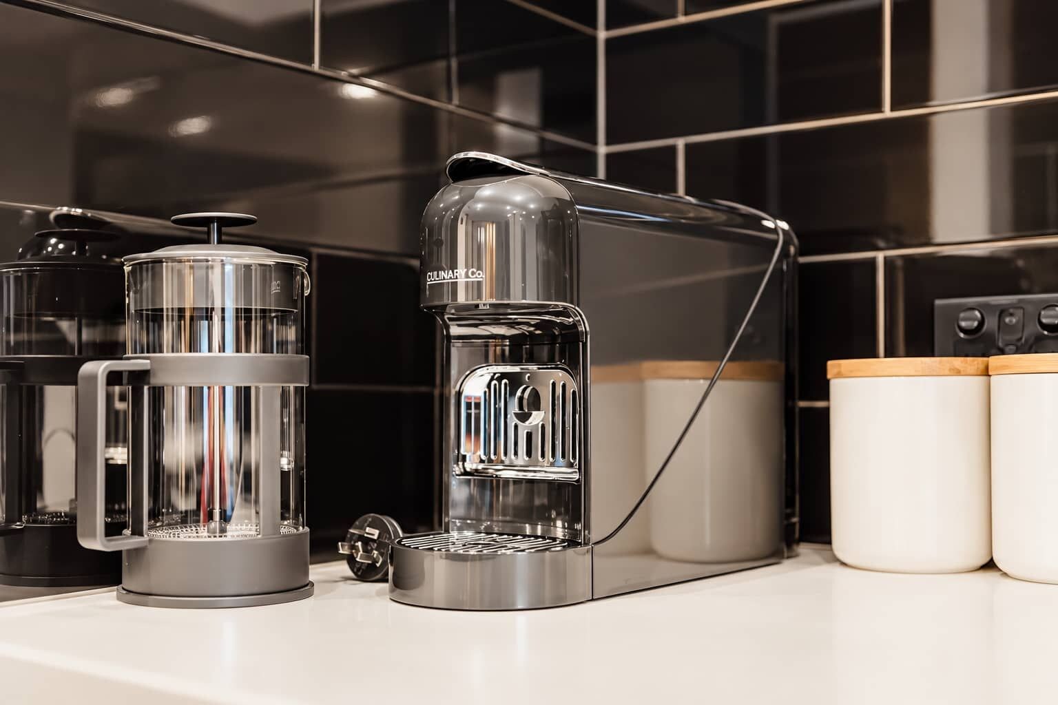 A kitchen with a coffee maker, a kettle, and a mug on the counter.