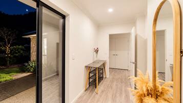 A modern interior with a glass door leading outside, a dining area with a table and chairs, and a large mirror.