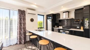 Una cocina moderna con una isla grande, taburetes de bar y vistas a zonas verdes.