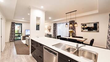 A modern kitchen with a built-in dishwasher, a dining area with a table and chairs, and a large window with curtains.