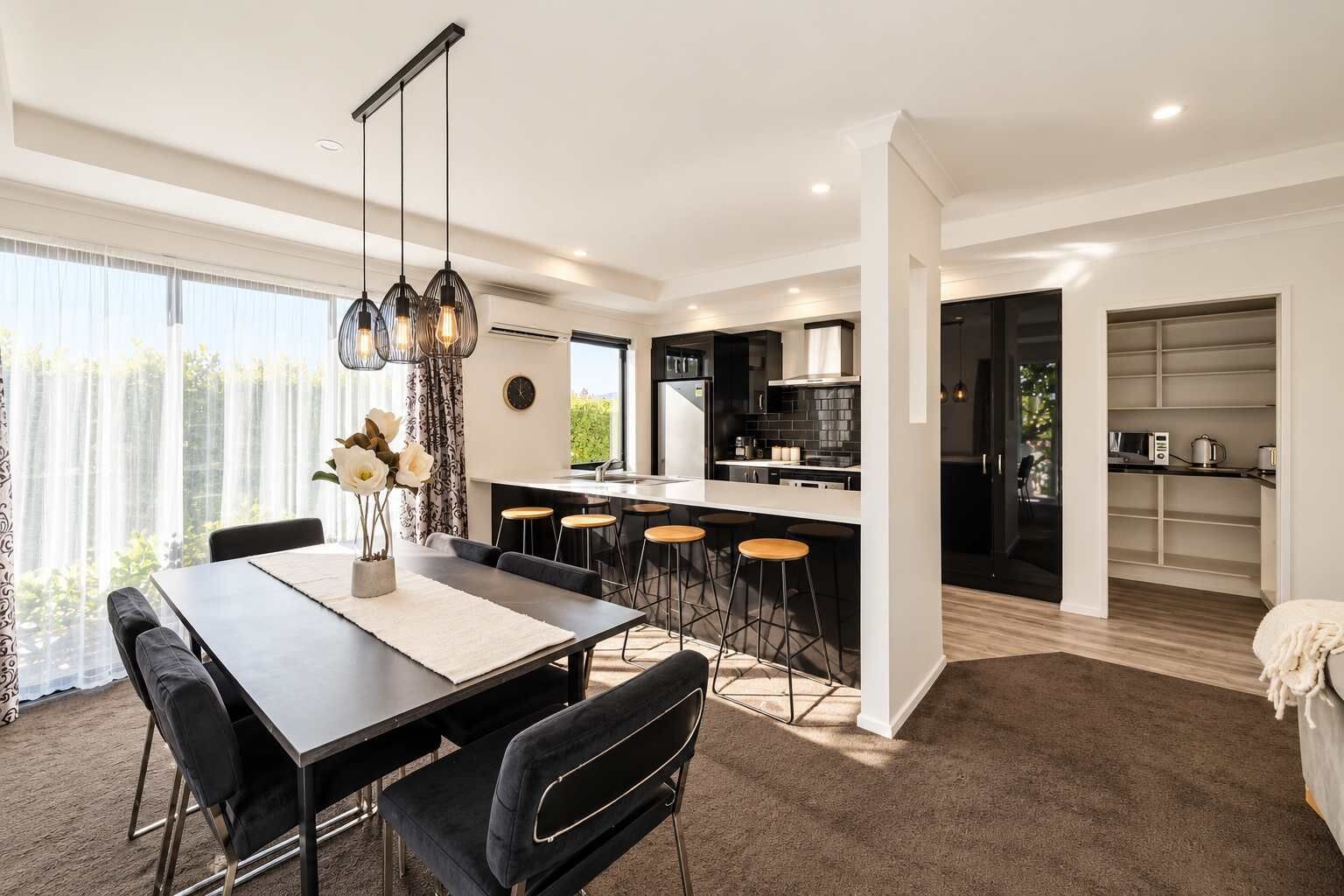 Een moderne keuken met een centraal eiland, barkrukken en hanglampen.
